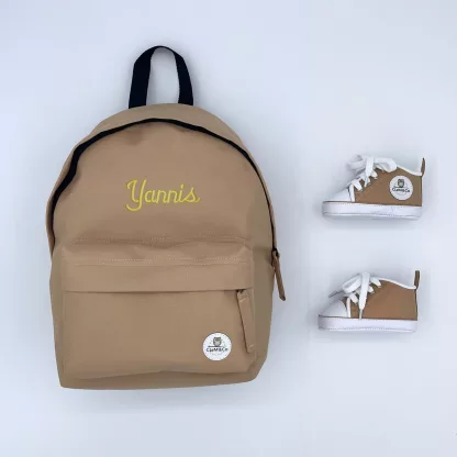 Coffret comprenant un sac à dos et des chaussures beiges avec le nom brodé Yannis